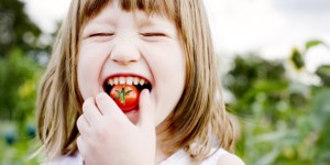 Young Girl(5-6) biting into cherry tomato